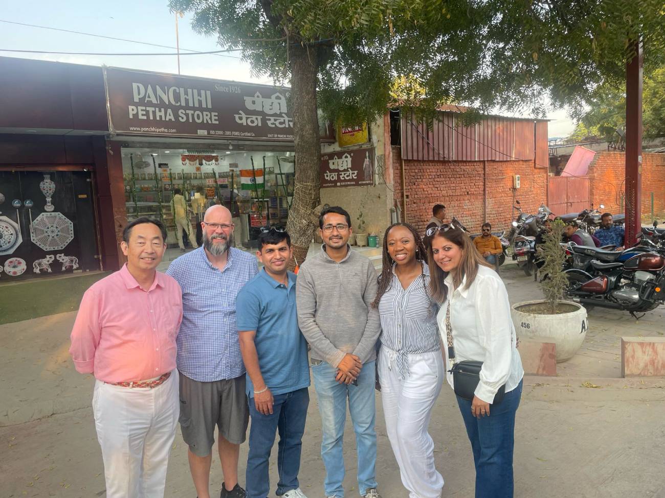 Tour guide with five international tourists during a Golden Triangle Tour standing in front of Panchhi Petha Store in Agra.
